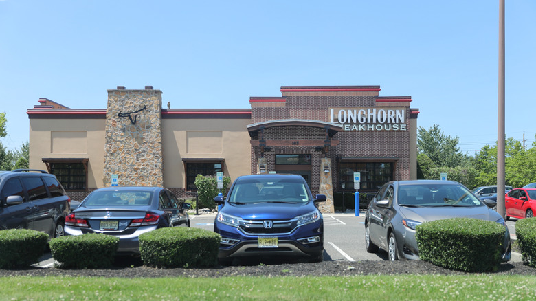 Cars in parking lot of LongHorn Steakhouse on bright sunny day.