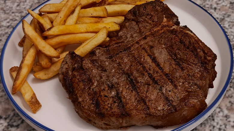 LongHorn Steakhouse T-bone on plate with fries.