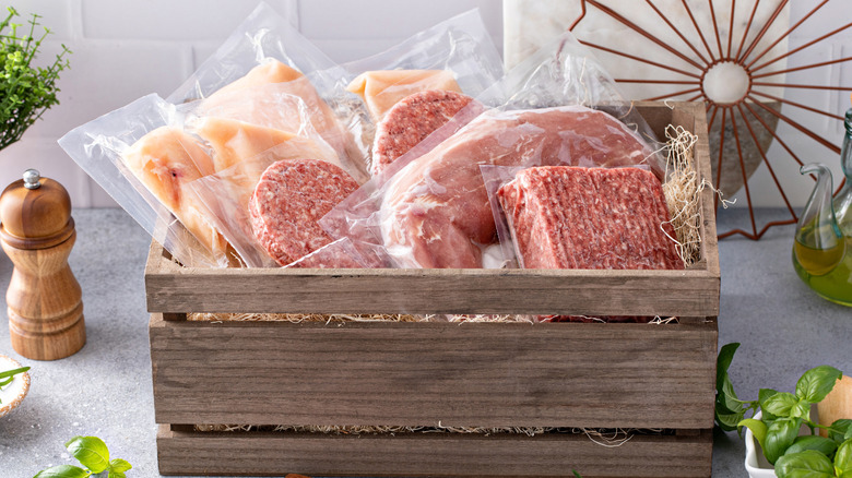 Wooden delivery box of various meat set on a counter with decorations.