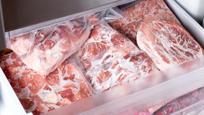 A draw full of sealed airtight packages of frozen raw pork chops.