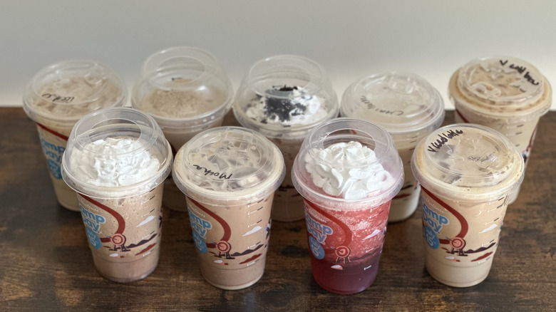 Lineup of plastic cups of Tim Hortons cold drinks on wooden table