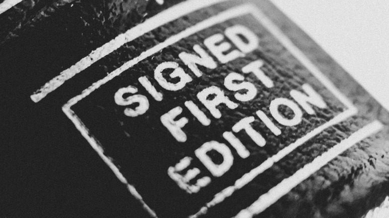 Close-up black-and-white image of a book that reads "signed first edition"