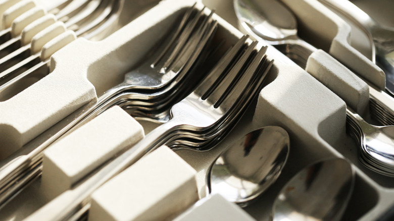 Forks and spoons neatly arranged in a silverware storage container.
