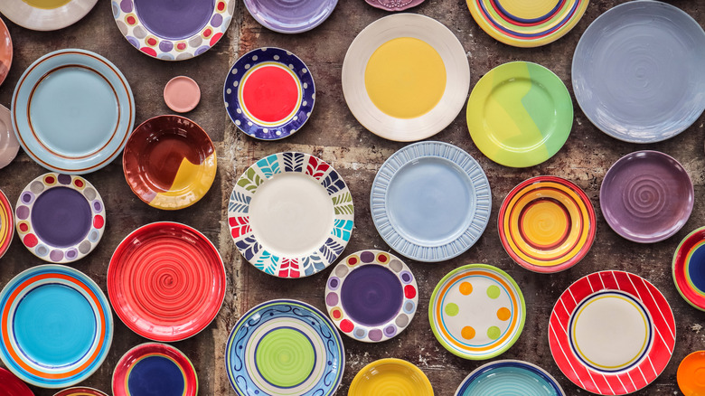 An assorted set of colorful plates with different patterns on a concrete floor.