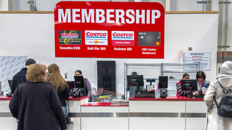 People waiting in line at the membership counter inside a Costco.