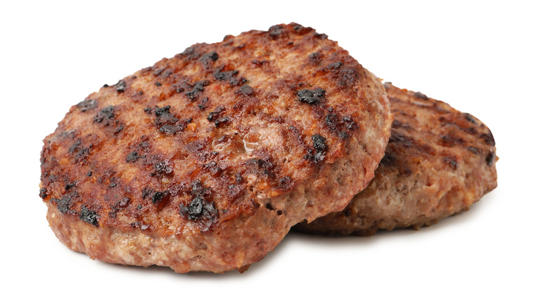 Grilled burgers resting on white background