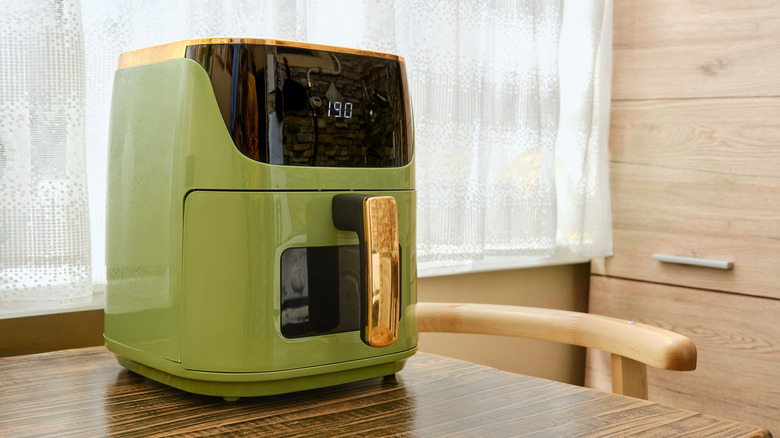 Preheating green air fryer on wooden table