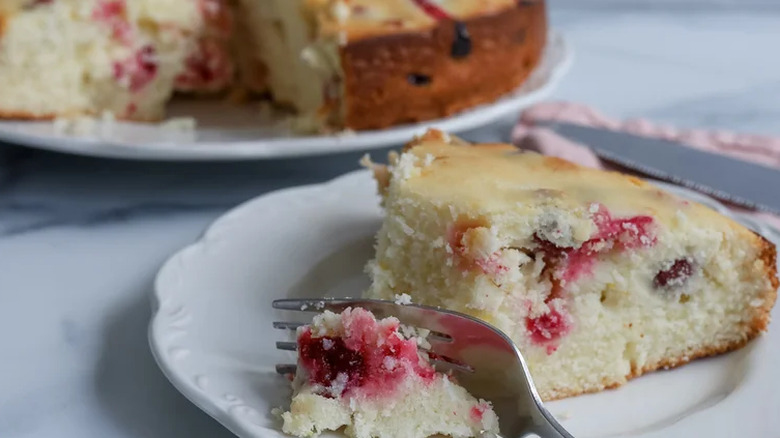 A slice of cranberry ricotta cake in a plate with a fork