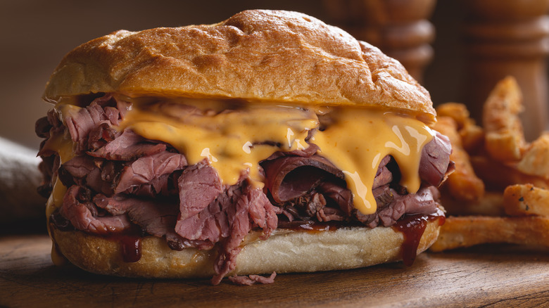 roast beef sandwich with cheese and sauce oozing out