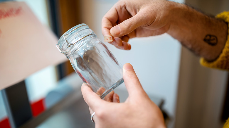 Person labeling glass jar at store