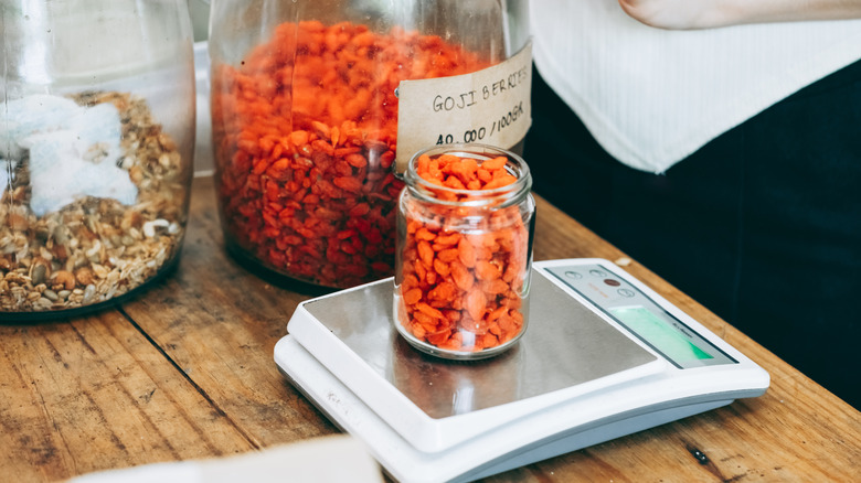 Goji berries in a glass jar being weighed at store