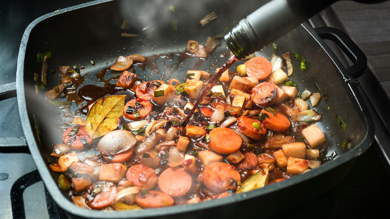 Pouring wine into sauteing vegetables
