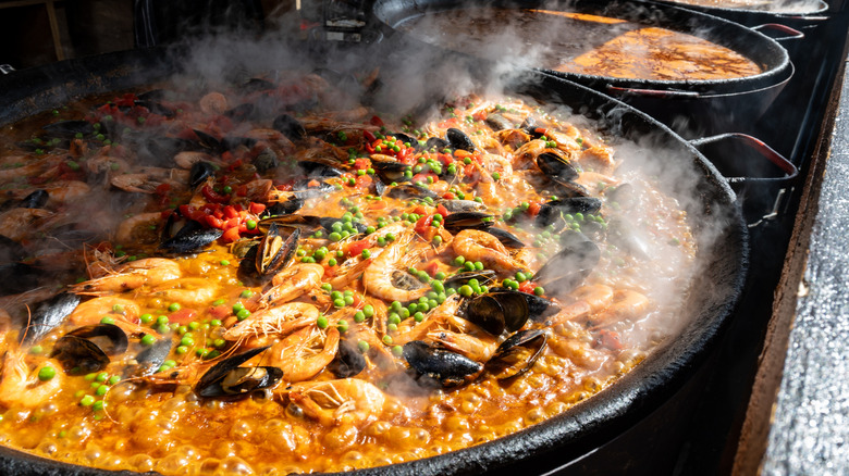 Paella pot simmering next to other pots of food