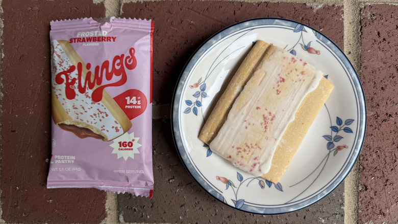 Single-serving package of Flings toaster pastry next to unwrapped pastry on plate