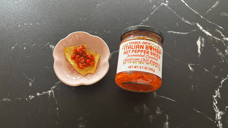 Trader Joe's Italian bomba sauce jar next to tortilla chip on small plate with sauce on it