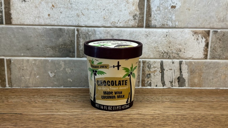 Trader Joe's Chocolate non dairy frozen dessert made with coconut milk in a tub on wooden counter