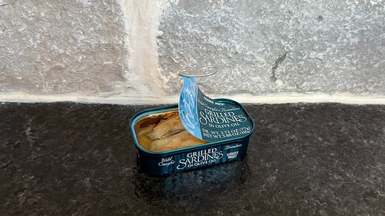 Halfway opened tin of grilled sardines in olive oil from Trader Joe's placed on a counter