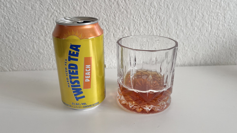 Can of peach Twisted Tea next to a glass