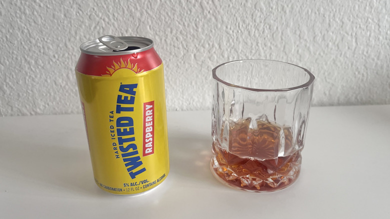 Open can of Raspberry Twisted Tea next to a glass