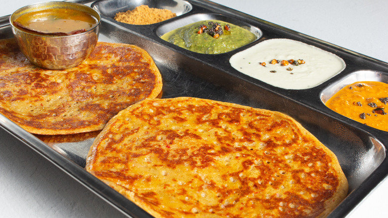 Two adai dosa served with sambhar, jaggery, and three chutneys
