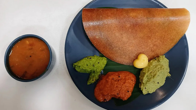 Dosa topped with heart shaped pat of butter, served with three chutneys and sambhar
