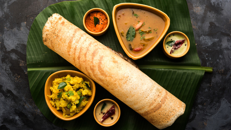 Paper dosa on banana leaf with chutneys, masala, and sambhar