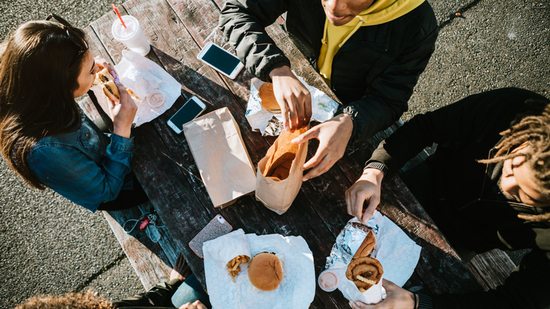 An ariel shot of a group of young people eating fast food at a picnic table