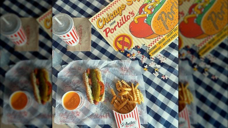 Fries, cheese sauce, a drink, and a Chicago dog on a checkered table with a Portillo's puzzle