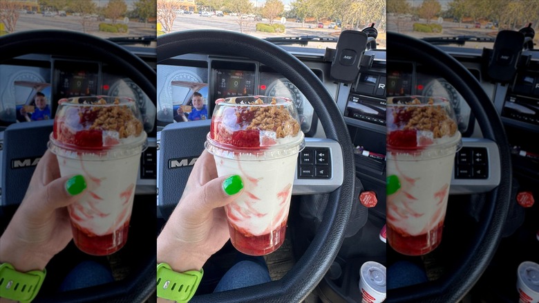 Hand holding strawberry cheesecake sundae from Checker's in car