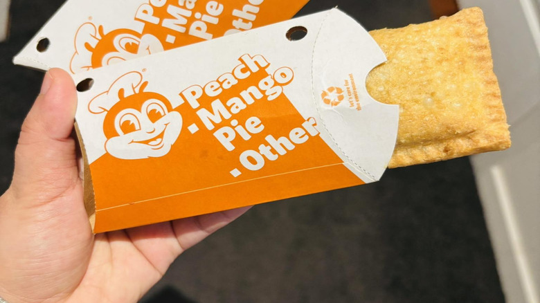 Hand holding Jollibee peach mango pie in wrapper