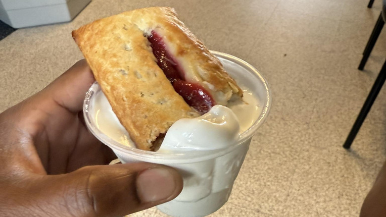 Hand holding McDonald's strawberry and cream pie in ice cream cup