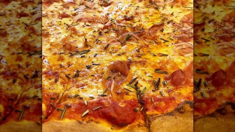 Cheese pizza sprinkled with rosemary and meat