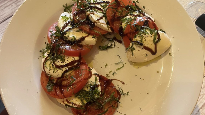 Mozzarella and tomato slices layered on a white plate with balsamic