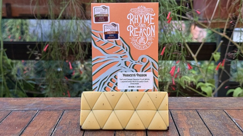 Bar of passionfruit chocolate resting at bottom of packaging on wooden table