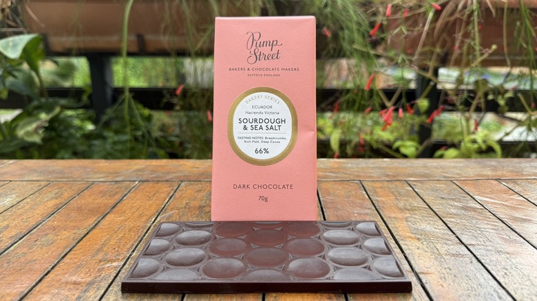 Bar of sourdough and sea salt chocolate beneath packaging on wooden table