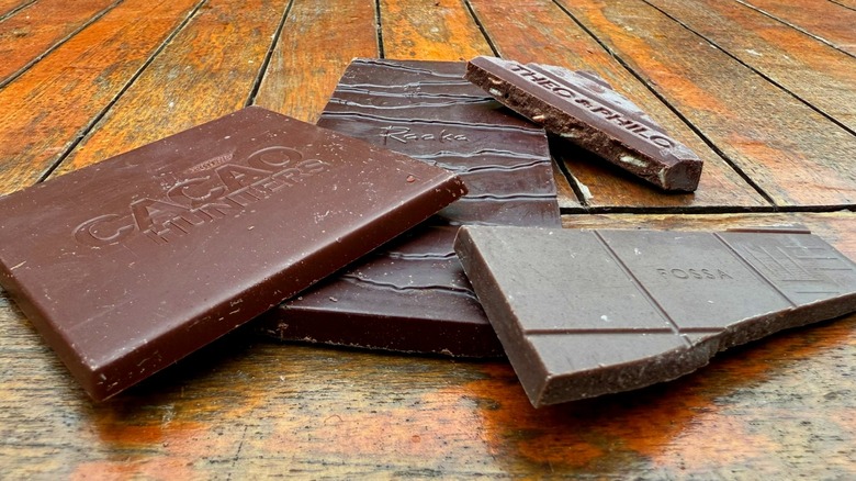 Four pieces of chocolate from different brands on wooden table