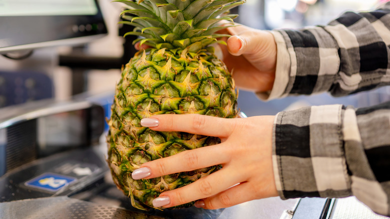 Hand scanning a pineapple at self-checkout station