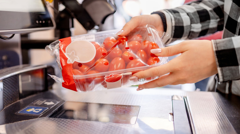 Hands scanning cherry tomatoes at a self-checkout station