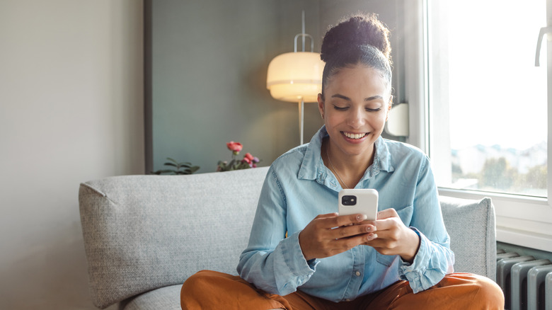 Woman using cell phone while sitting on couch