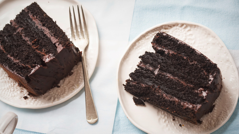Two slices of dark chocolate cake made with cola on plates