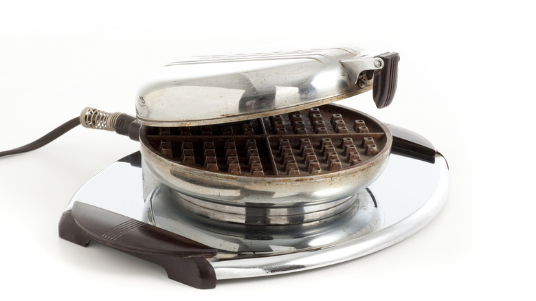 vintage electric waffle iron in chromed steel with bakelite handles, shown on a white ground