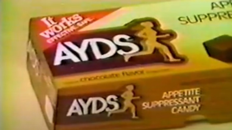 A still from a vintage ad showing a close-up of a box of Ayds candy on a yellow background