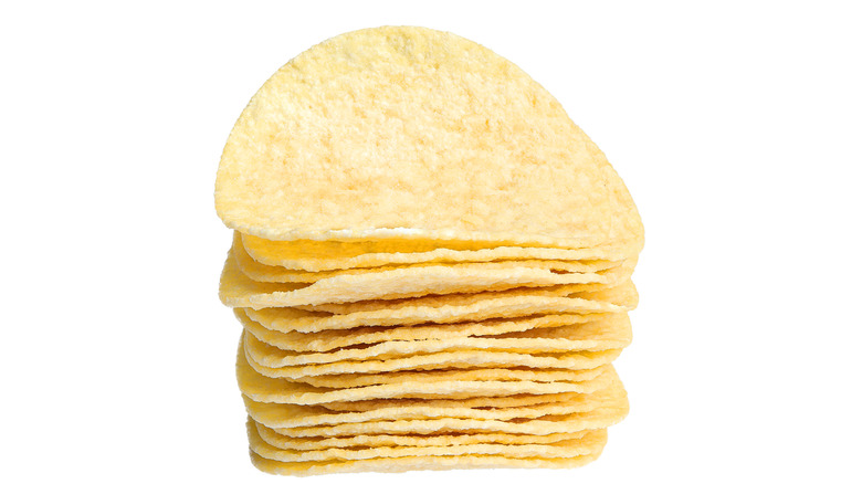 A stack of thin, crispy potato chips isolated on a white background