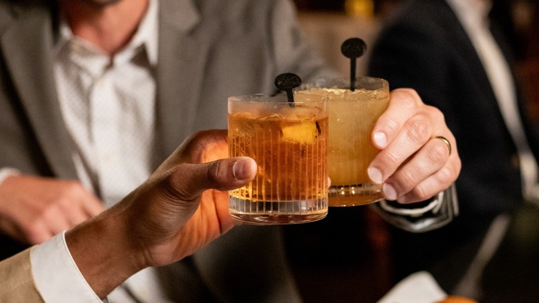 Two hands clinking cocktails at The Capital Grille