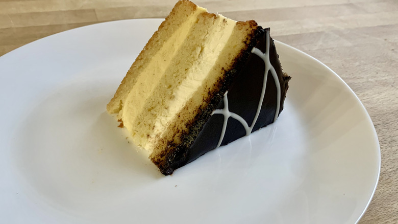 boston cream pie cake slice on white plate with wood background