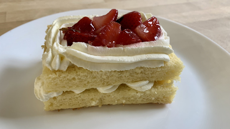 strawberry shortcake slice on white plate with wood background