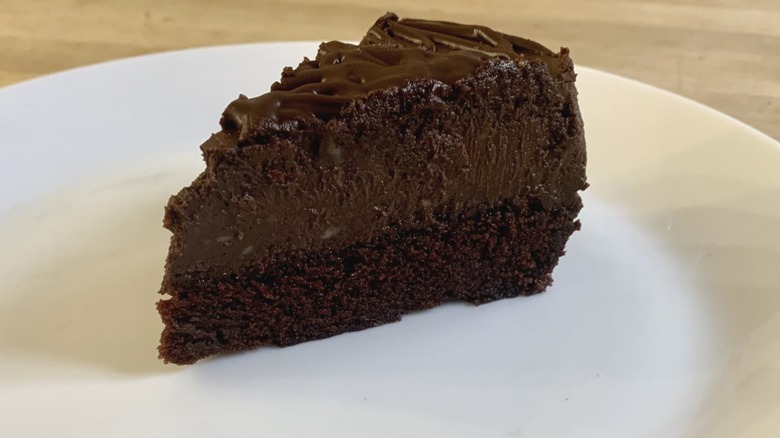 chocolate mousse cake slice on white plate with wood background