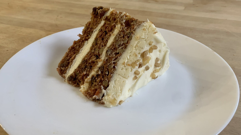 carrot cake slice on white plate with wood background