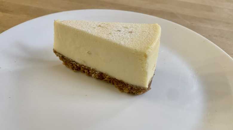 plain cheesecake slice on white plate with wood background