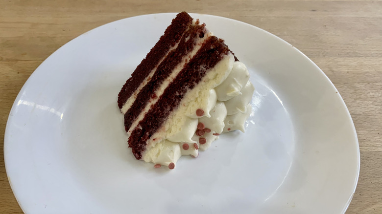 red velvet cake slice on white plate with wood background